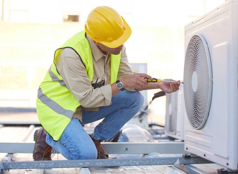 A person replacing an HVAC air filter in a residential hallway vent before winter.