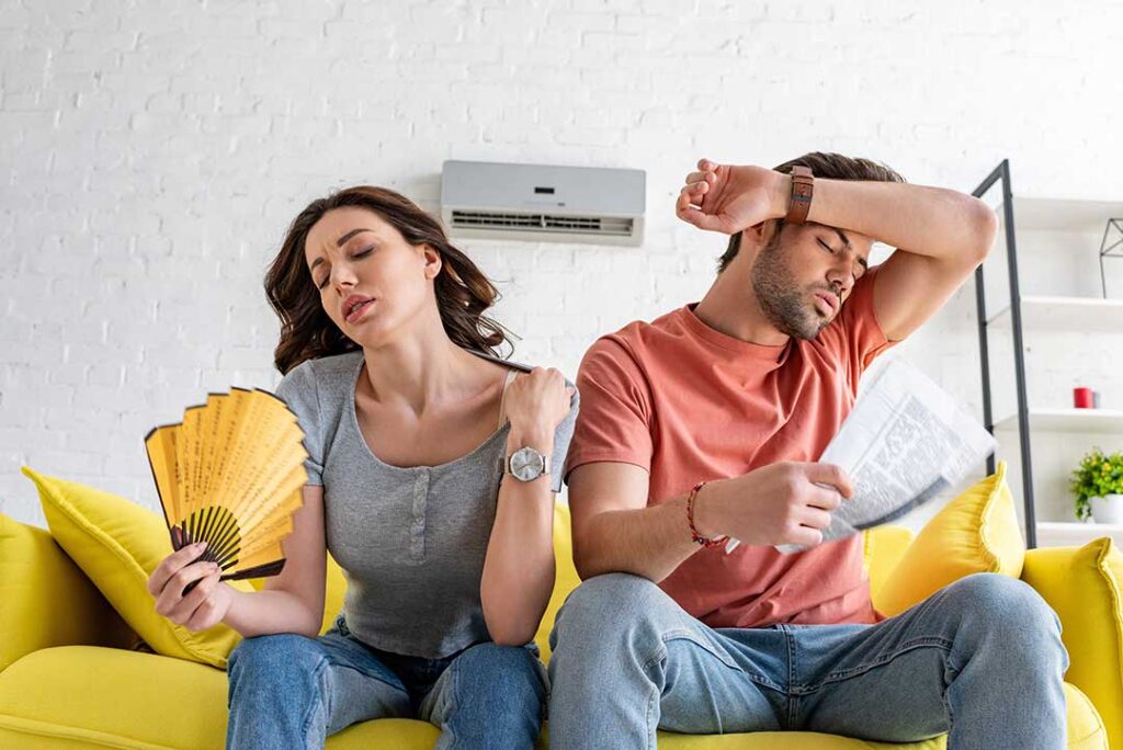 A homeowner listening to a loud air vent while examining a central HVAC system indoors.